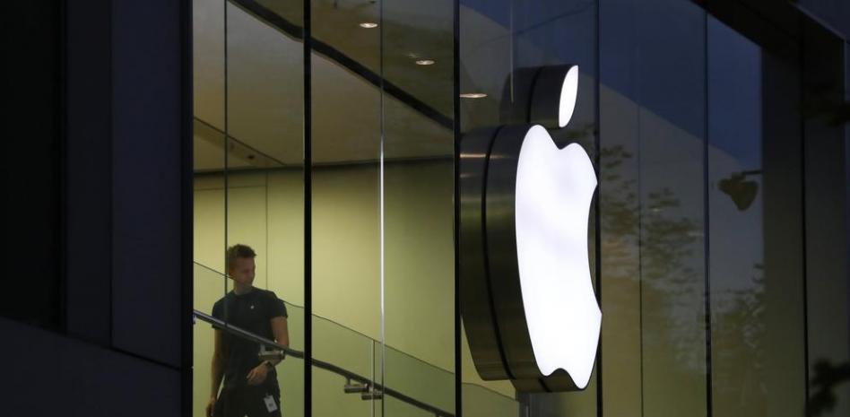 Un empleado de Apple camina junto al logotipo de la compañía en una tienda Apple en Fráncfort (Alemania) EFE