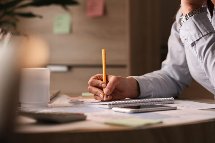 Unrecognizable businesswoman taking notes while working in the office. Volver desde el silencio y seguir avanzando
