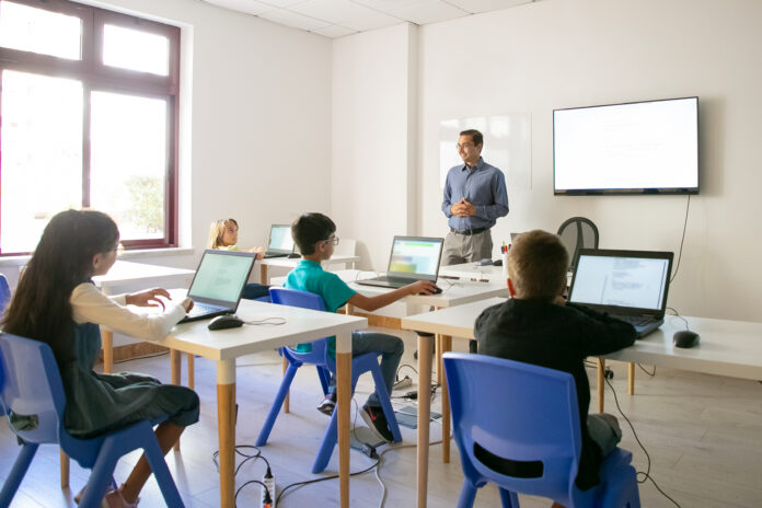 Confident teacher explaining lesson to pupils El multilingüismo transforma las aulas y plantea nuevos retos a los docentes